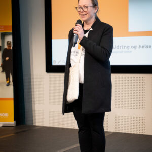 Marit Stranden står med en mikrofon på en scene. Foto: Alexandra Dahlen.