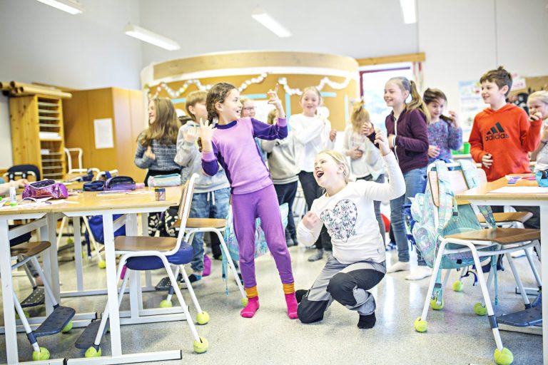 Barn i et klasserom danser og synger. Foto.