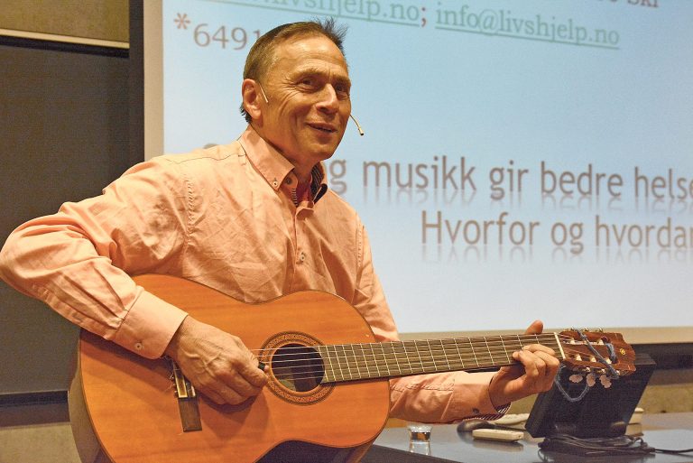 Audun Myskja spiller gitar. Han har kort hår, og har på seg en lys skjorte.