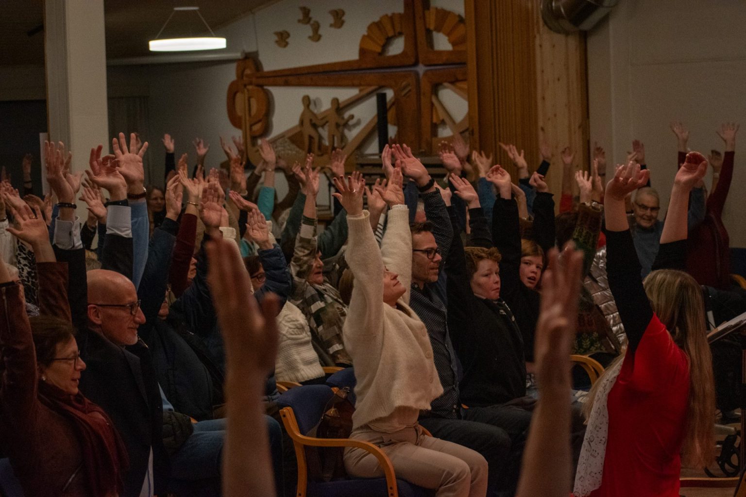 Publikum strekker hendene i været under Buen helsekor sin julekonsert 2024. Foto: Gonzalo Sentana.