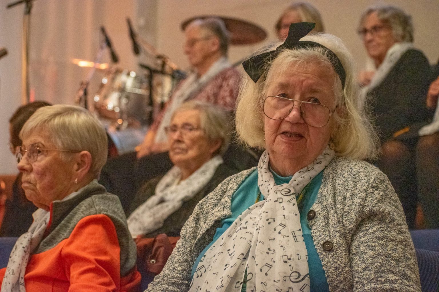 Eldre kvinne med sort sløyfe i håret sitter sammen med andre i et kor. Foto: Gonzalo Sentana.