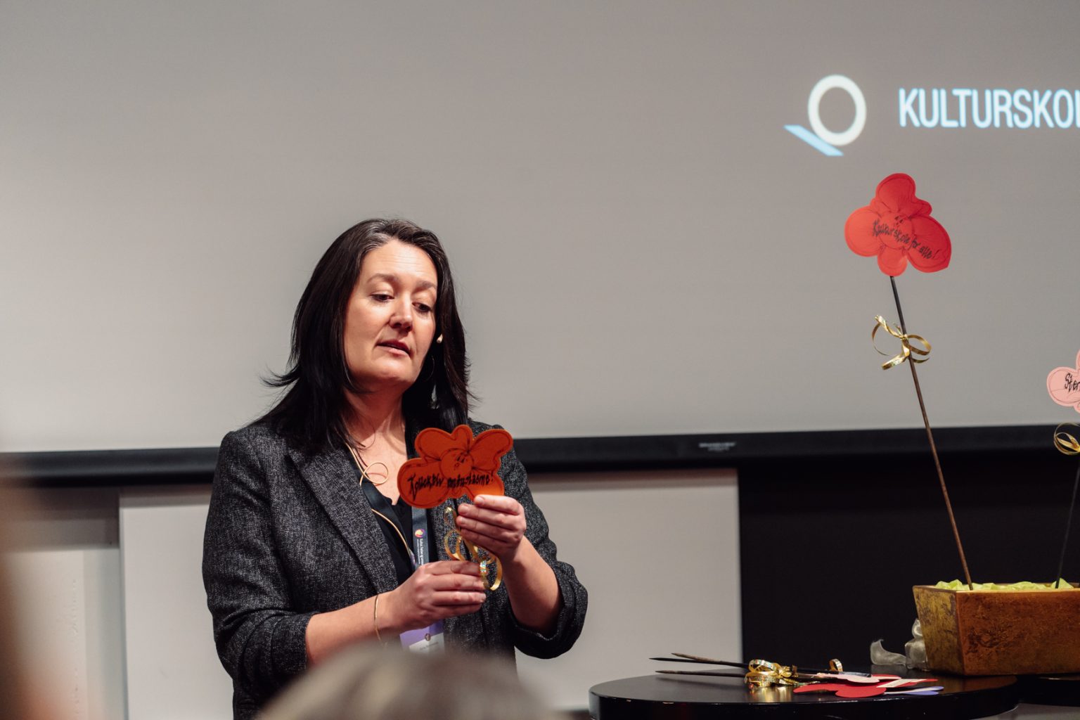 Anna Rennemo holder presentasjon. Hun har mørkt, skulderlangt hår. Hun har på seg en mørkegrå blazer. Foto: Christian Trustrup, TA-Kreativ.