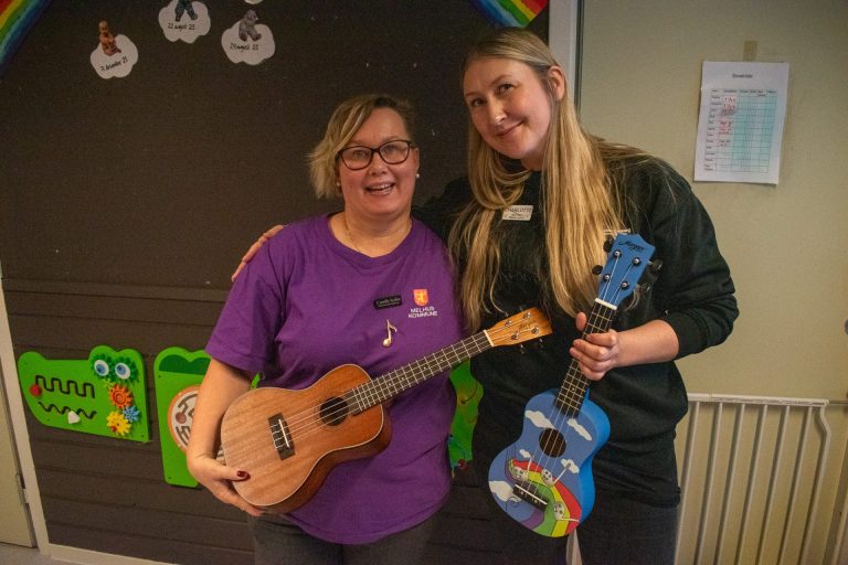 Camilla Stafne og Charlotte Stav står ved siden av hverandre og smiler til kamera. De holder begge i hver sin ukulele. Foto: Gonzalo Sentana.