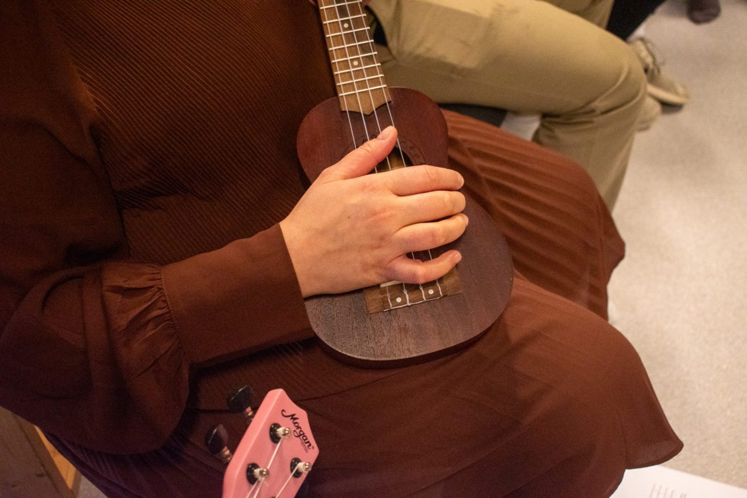 Utsnitt av en arm som holder i en ukulele. Foto.