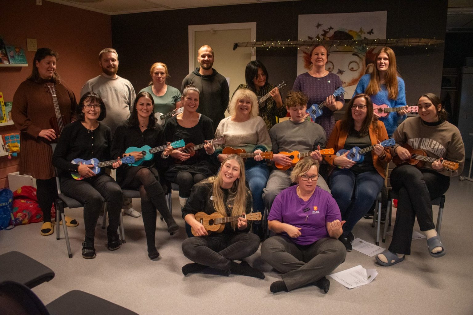 Gruppebilde av ansatte i Kosekroken barnehage. Foran dem sitter Charlotte Stav og Camilla Stafne på gulvet. Flere av personene i gruppebildet holder en ukulele. Foto: Gonzalo Sentana.