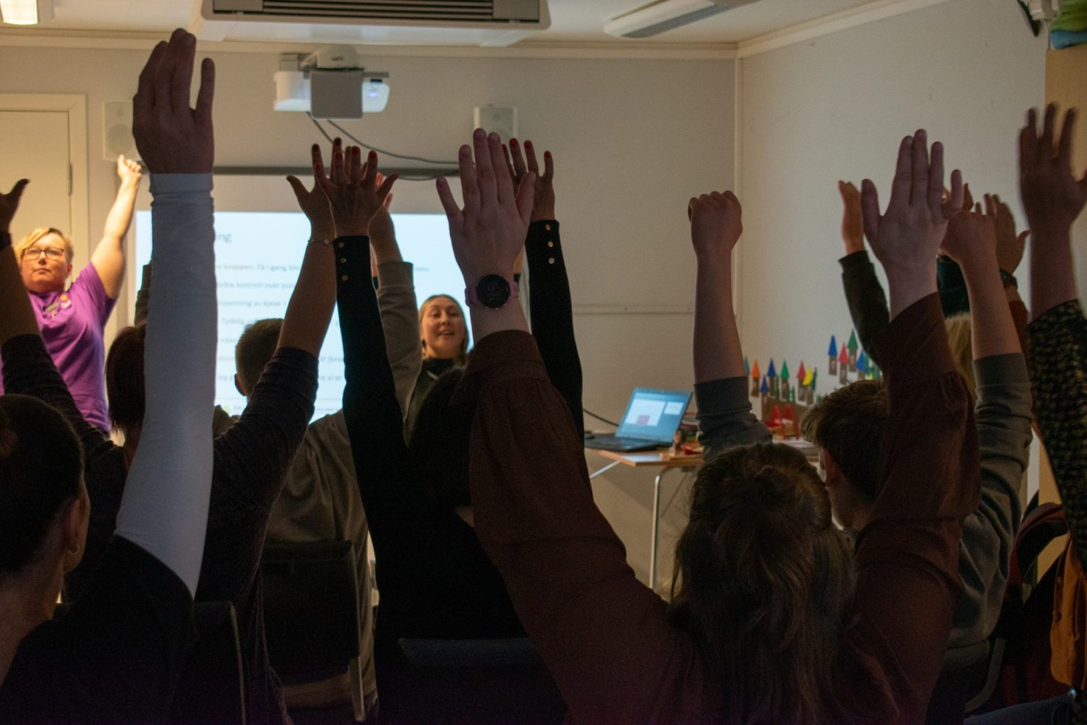 Flere personer holder begge armene i været. Vi kan så vidt skimte Camilla Stafne og Charlotte Stav i bakgrunn. Foto: Gonzalo Sentana.