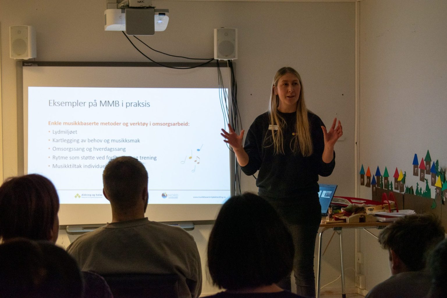 Charlotte Stav har langt lyst hår, og en sort genser og bukse. Hun står foran en gruppe personer og holder foredrag. Foto: Gonzalo Sentana.