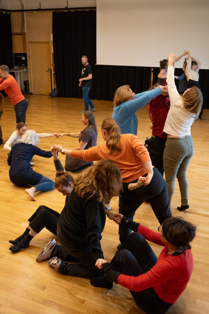 Mange personer danser sammen i en sal. Bildet er tatt under danseseminaret "Å skape meningsfulle dager". Foto: Alexandra Dahlen.