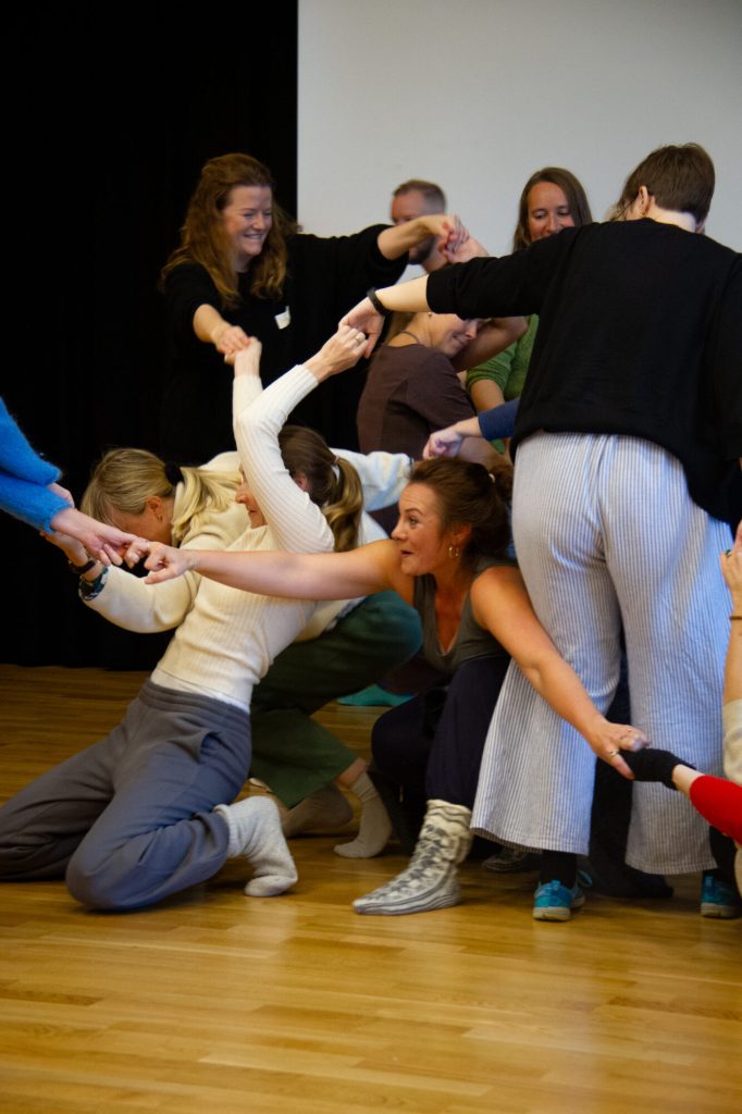 Flere personer står samlet i en haug. Alle holder hverandre i hendene. Bildet er tatt under danseseminaret "Å skape meningsfulle dager". Foto: Alexandra Dahlen.