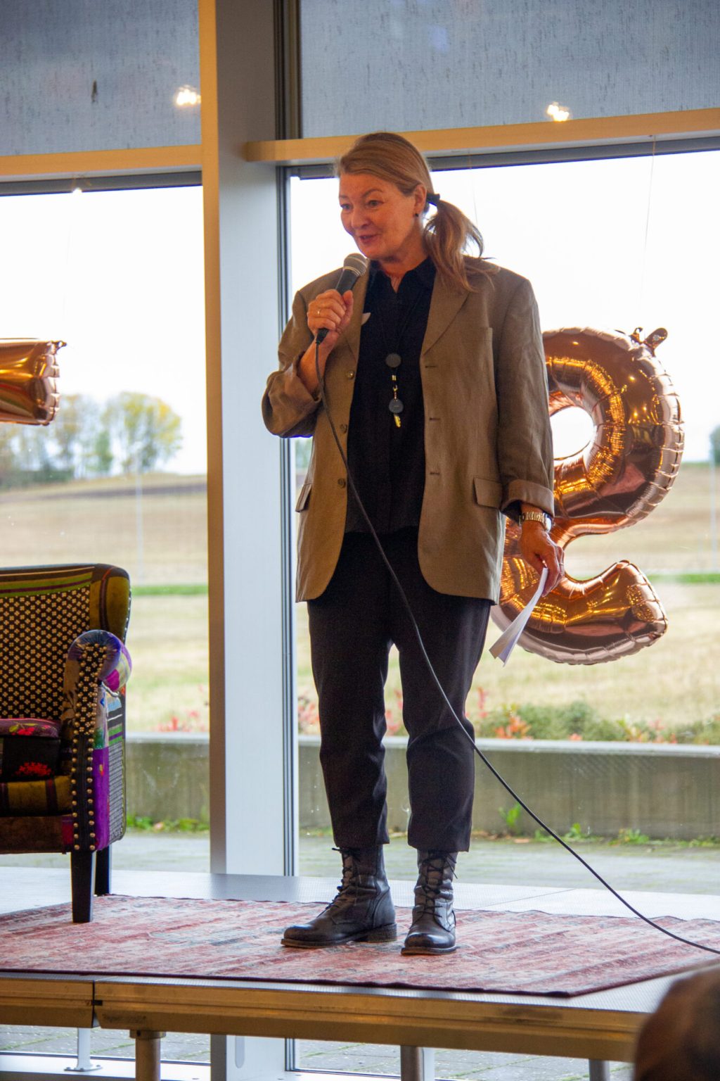 Siri Wigdel står på scenen og snakker i mikrofonen. Foto.