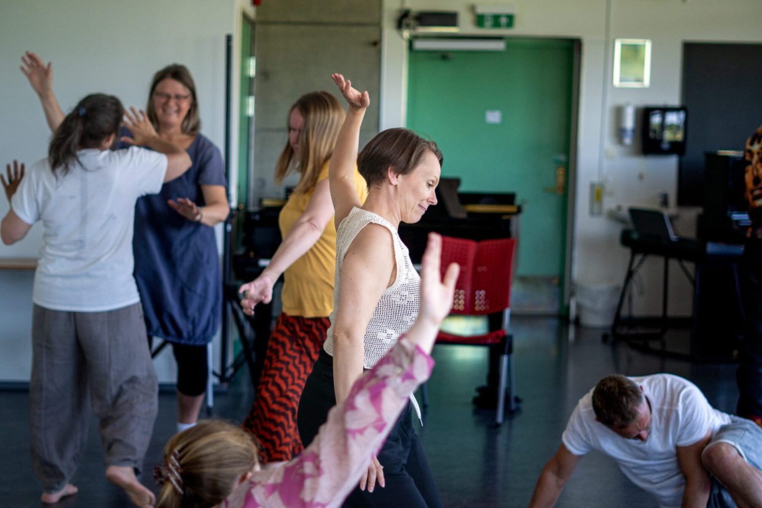 Elli Isokoski danser sammen med andre mennesker i et klasserom. Foto.