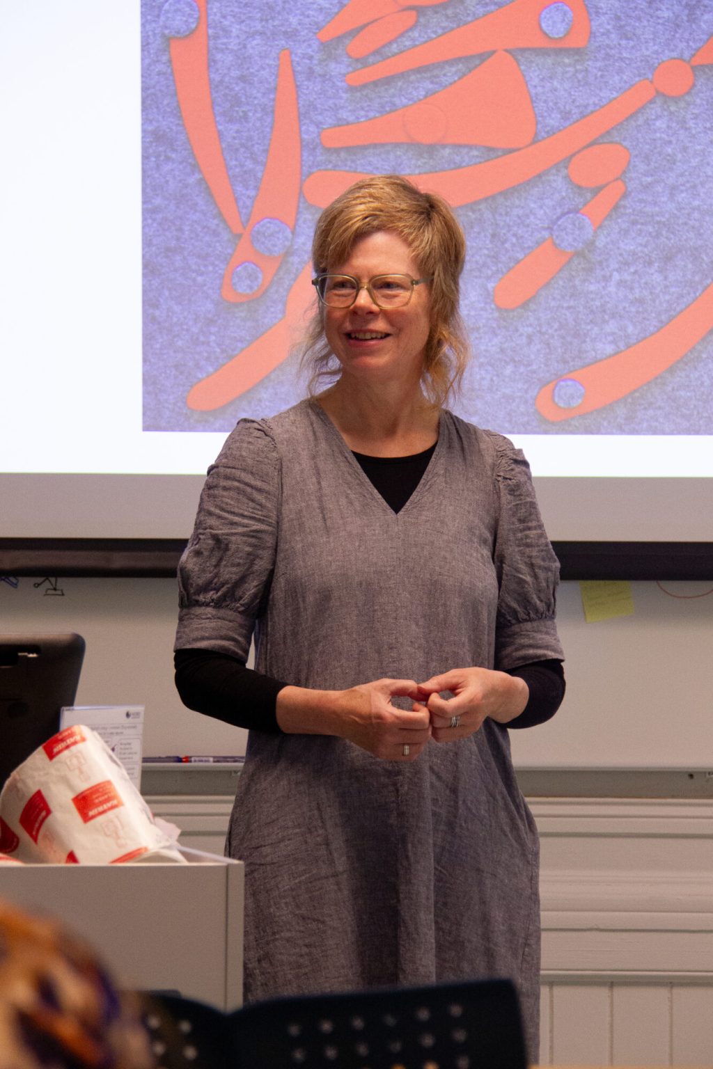 Anne Helga Henning står foran i et klasserom. Foto.