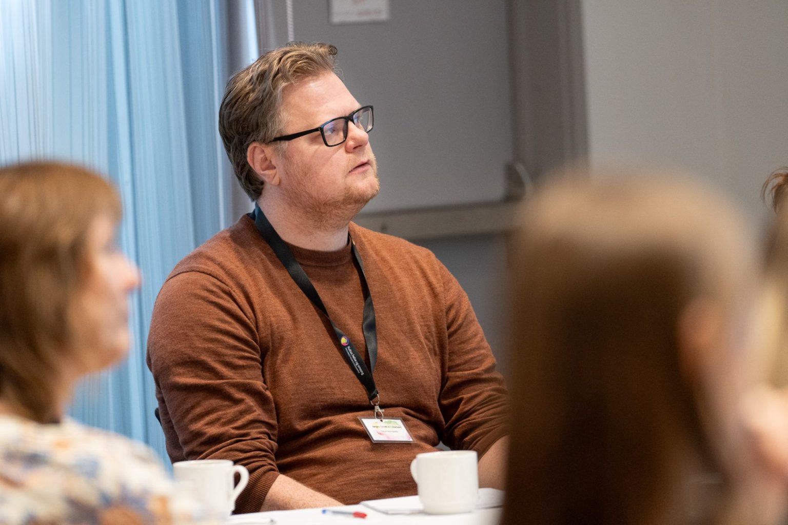 En mann sitter sammen med andre og lytter til et foredrag.