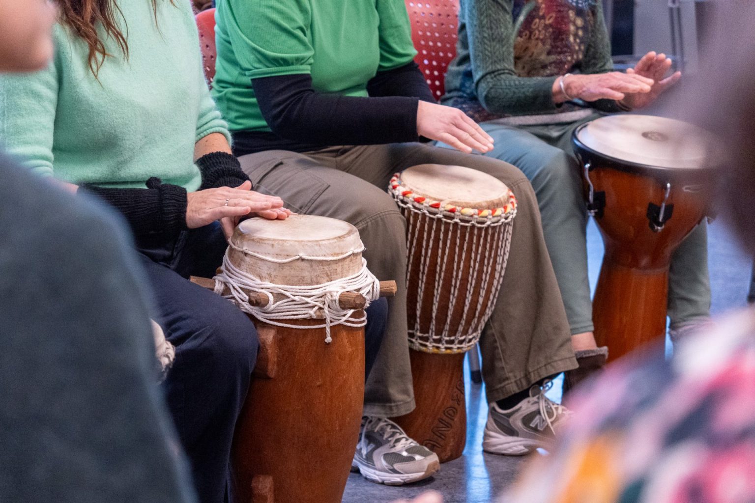 Flere personer sitter sammen og slår på hver sin tromme.