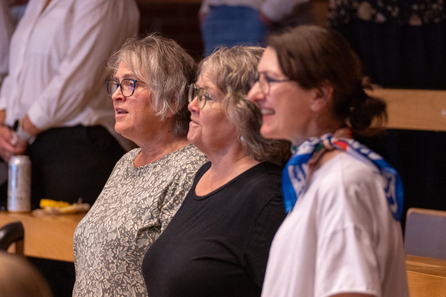 Tre kvinner står sammen i et auditorium.