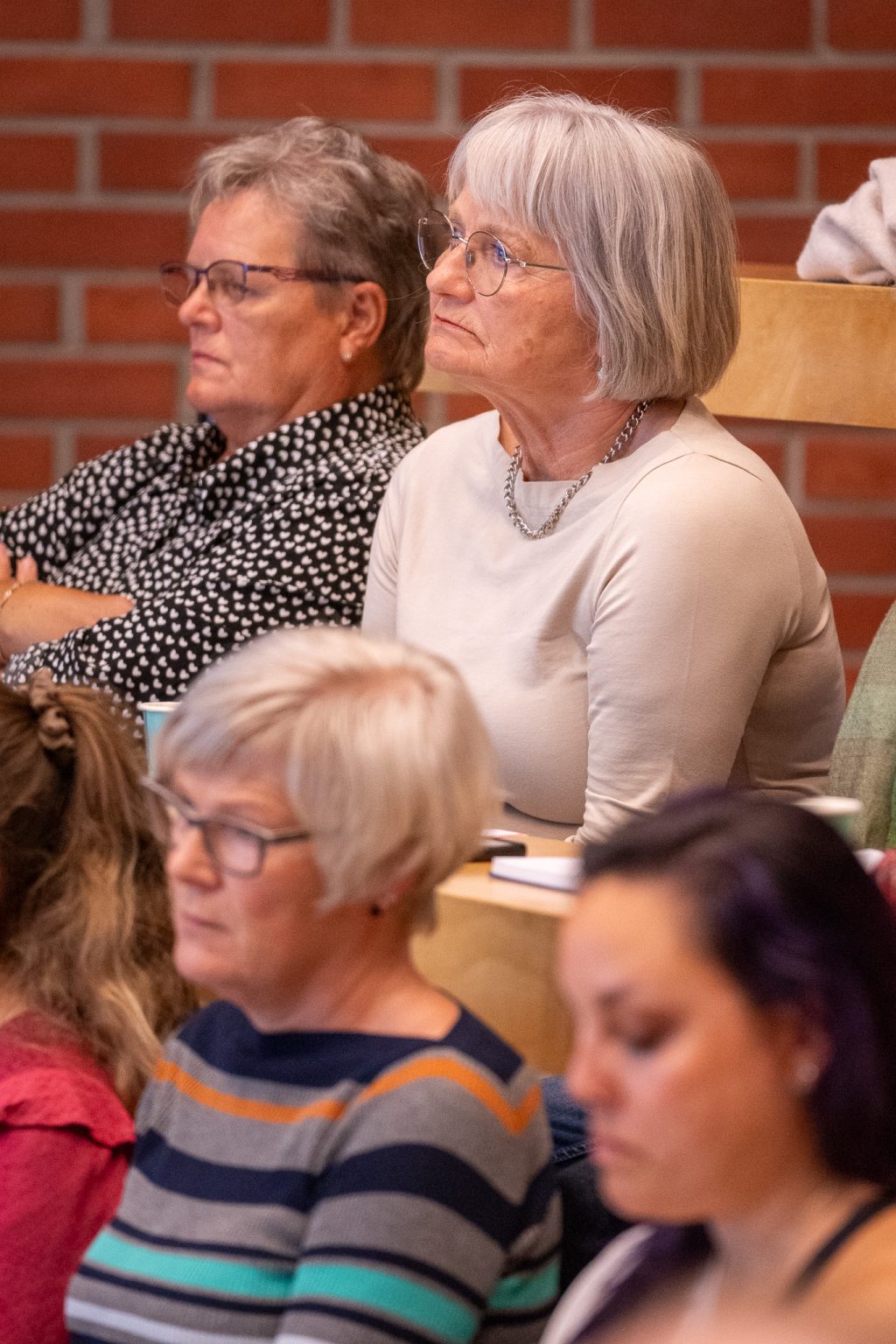 En kvinne sitter sammen med andre i et auditorium.