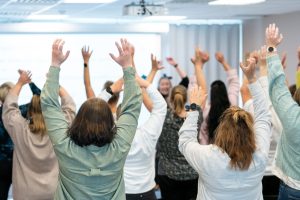 Mange personer står samlet og strekker hendene mot taket.