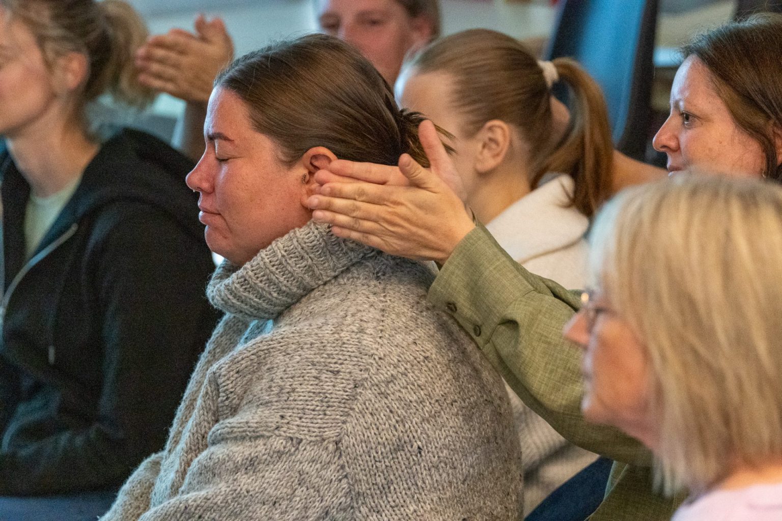 Flere personer sitter samlet på gulvet.