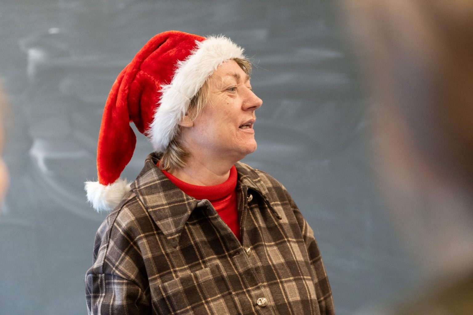 En kvinne med nisselue står i et klasserom.