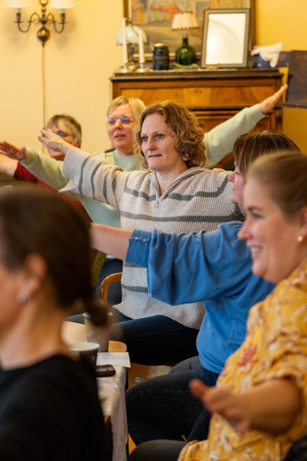 Flere kursdeltakere sitter samlet og beveger armene.