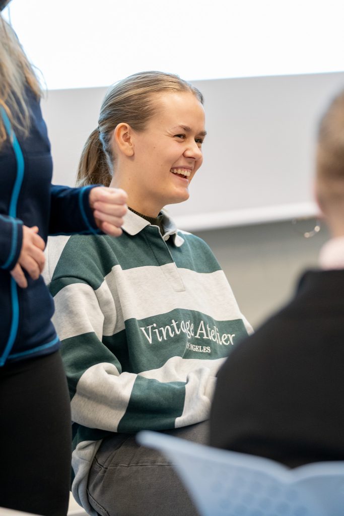 En kvinen sitter sammen med andre og ler.