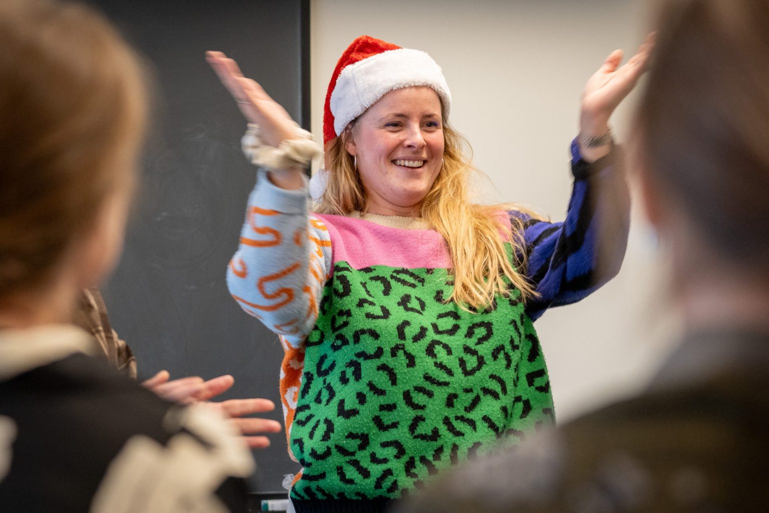 En kvinne med nisselue smiler og klapper med hendene.