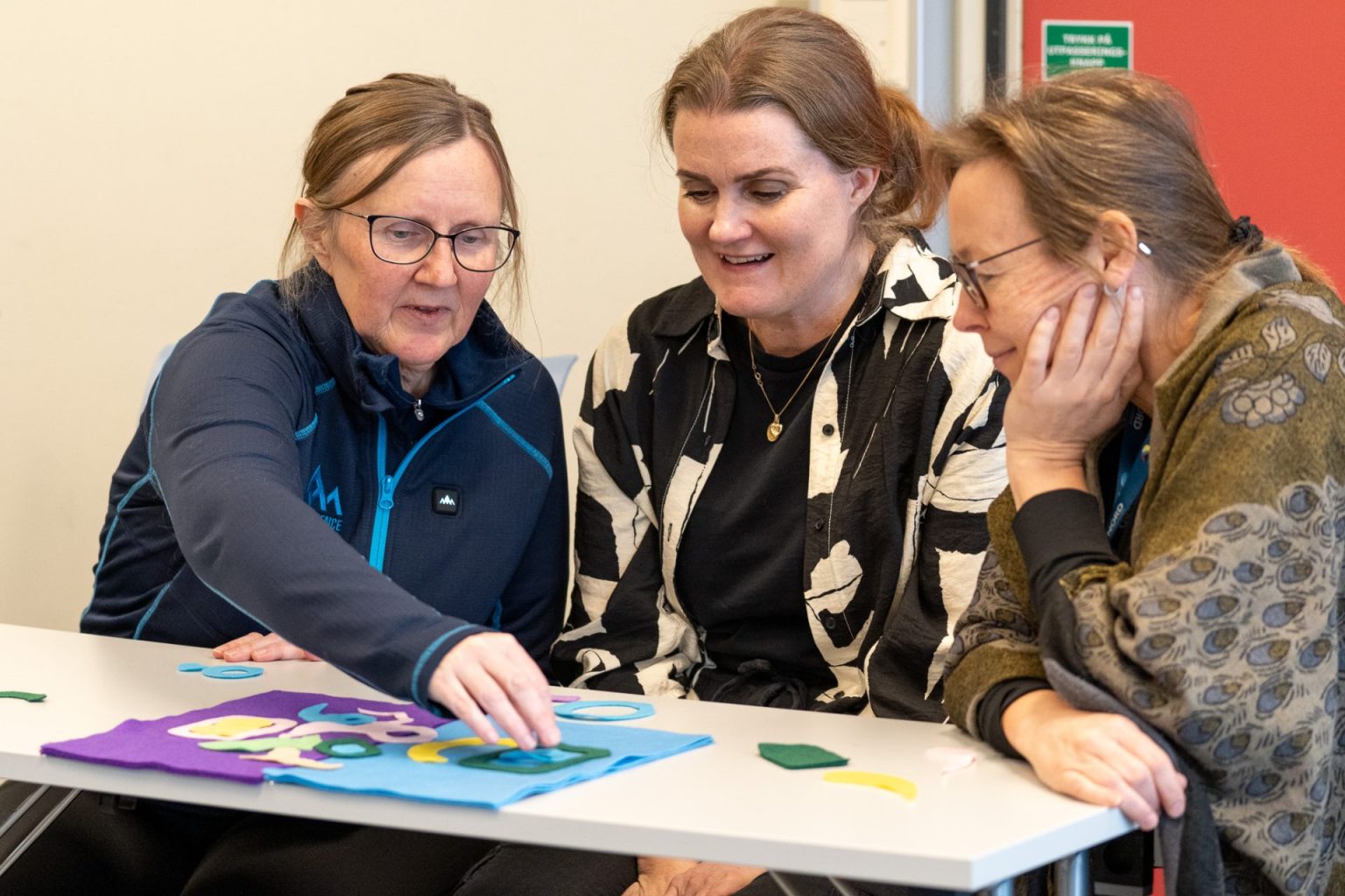 Tre kvinner sitter sammen og lager mønster med bruk av filt.