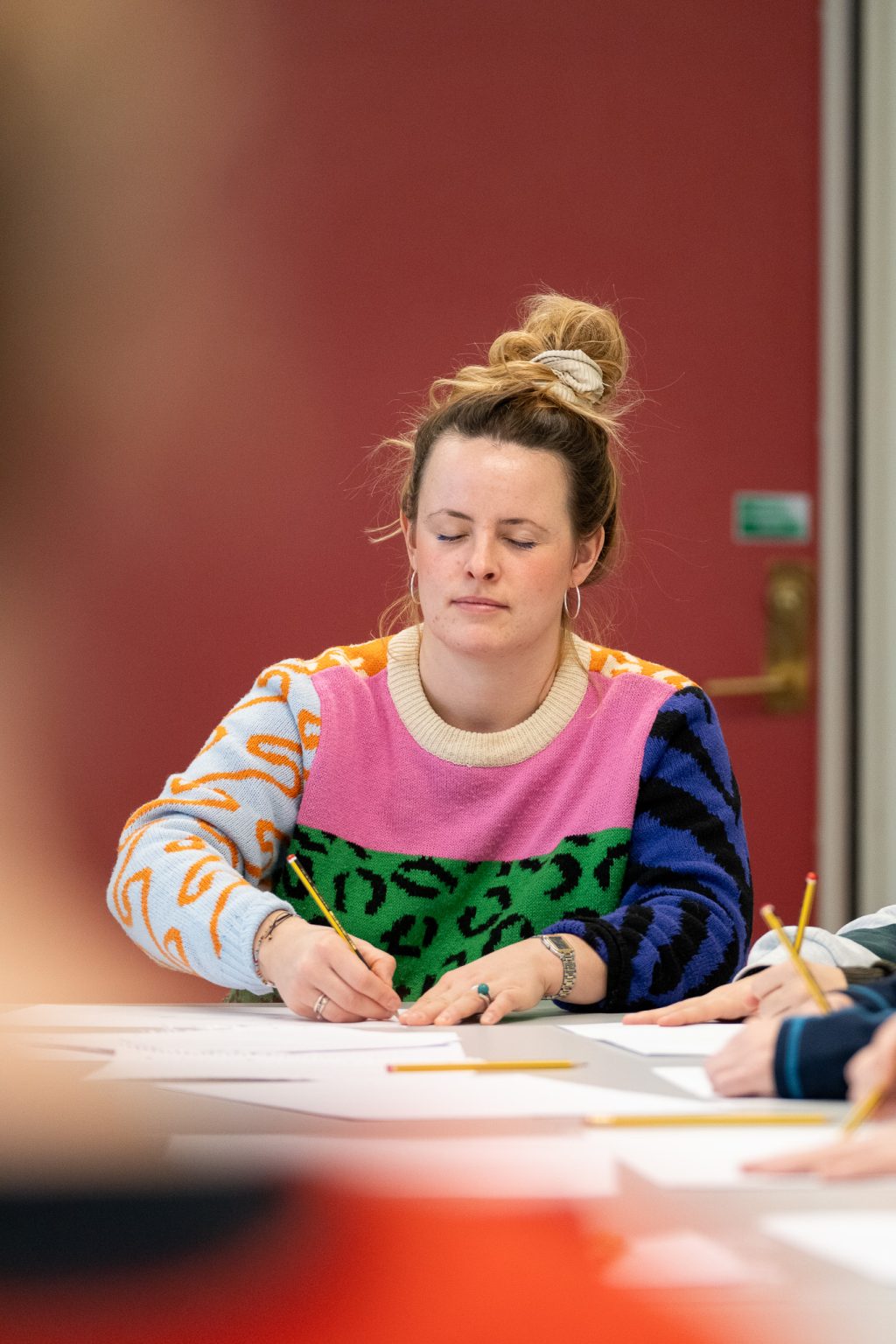 En kvinne sitter med lukkede øyne og tegner.