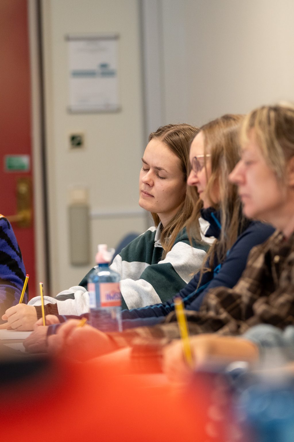 Tre kvinner sitter sammen og tegner med lukkede øyne.