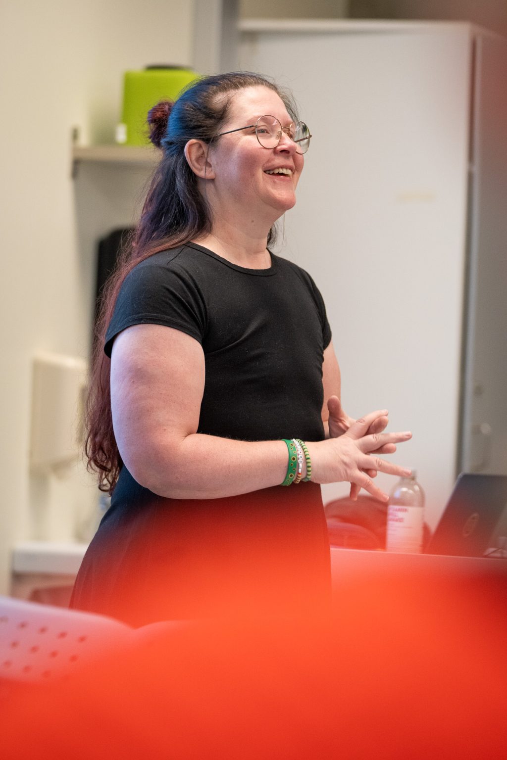 En kvinne står i et klasserom og smiler.