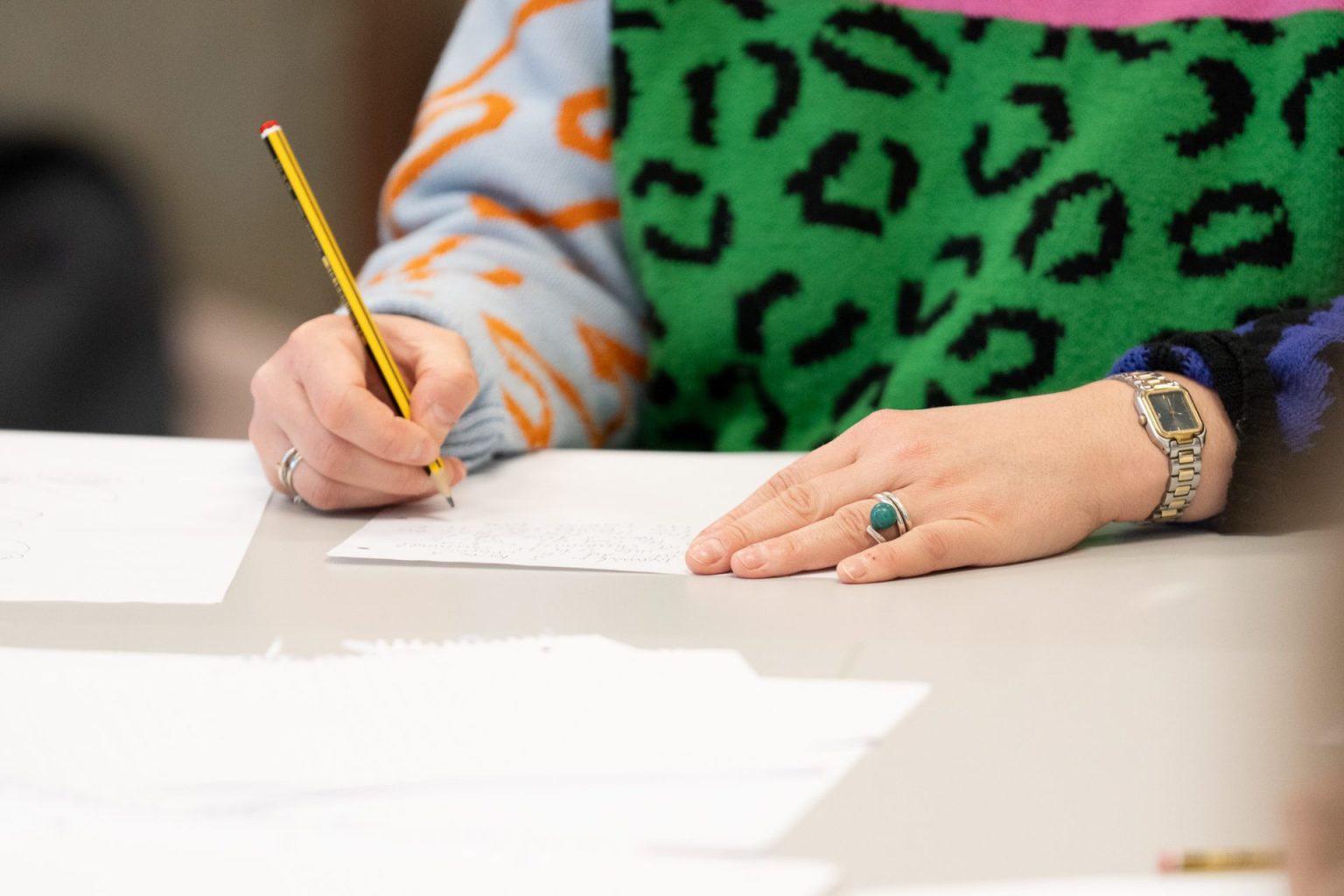 Hender som skriver på et ark.