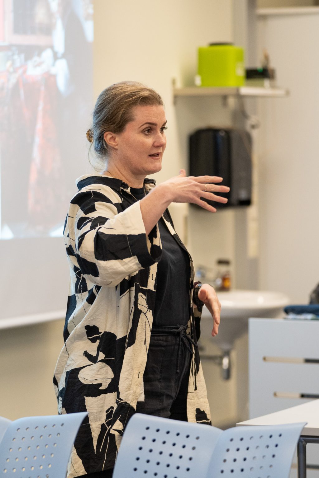 En kvinne står i et klasserom og snakker.