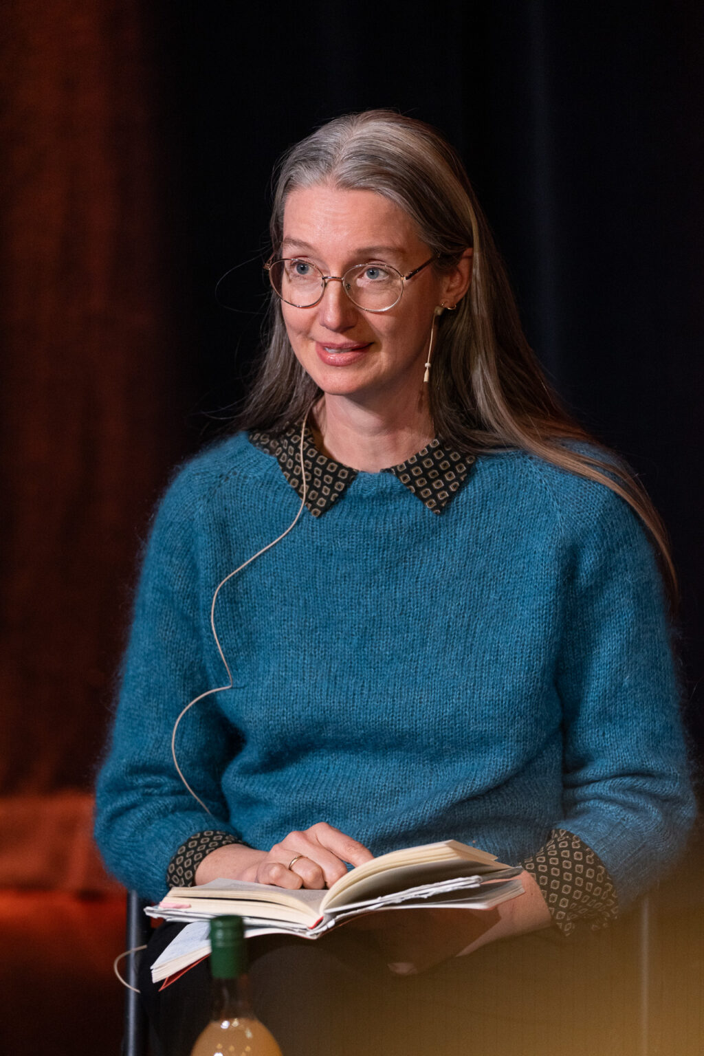 Liv Bjørnhaug Johansen leser bok på scenen.