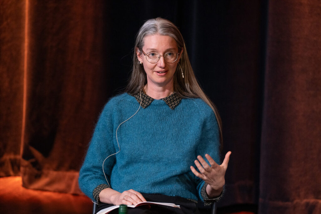 Liv Bjørnhaug Johansen leser bok på scenen.