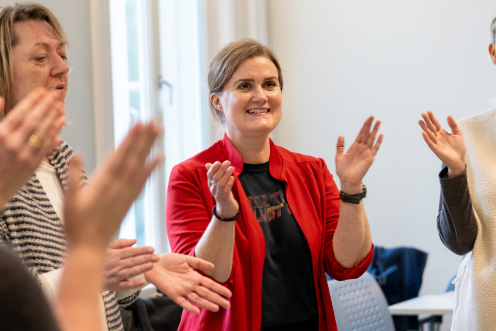 Studenter står sammen. De smiler og klapper.