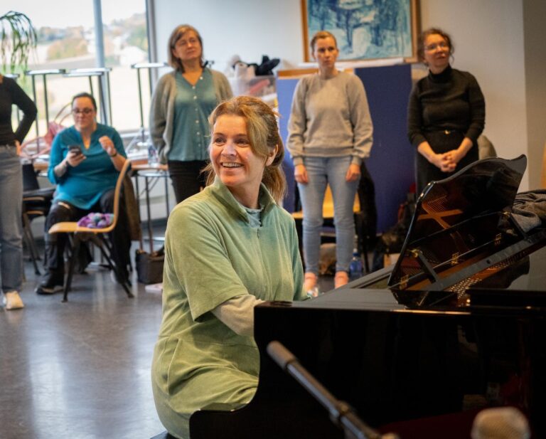 Grete Daling spiller piano foran studenter ved videreutdanningen i musikkbasert miløbehandling.